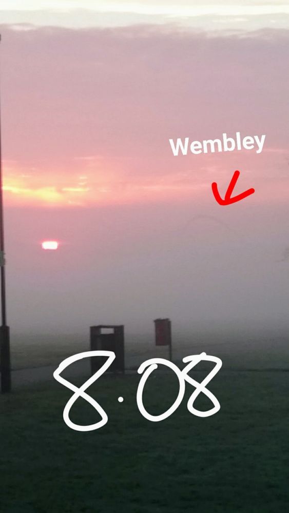 8:08 am, Wembley Stadium through heavy mist with the sunrise in view.